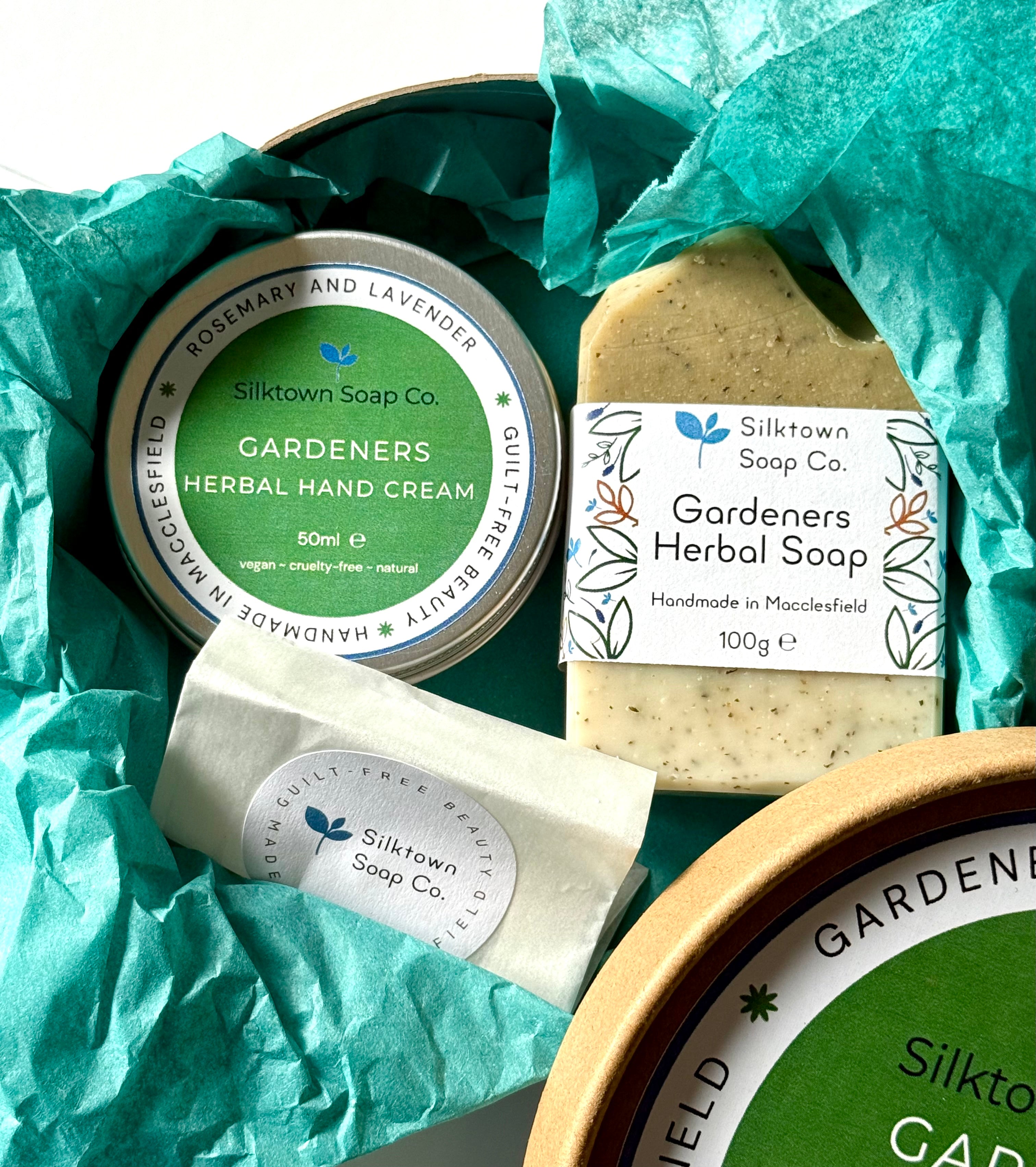Silktown Soap Co. Natural Skincare products including a hand cream, soap bar, and tea bag on green tissue paper.