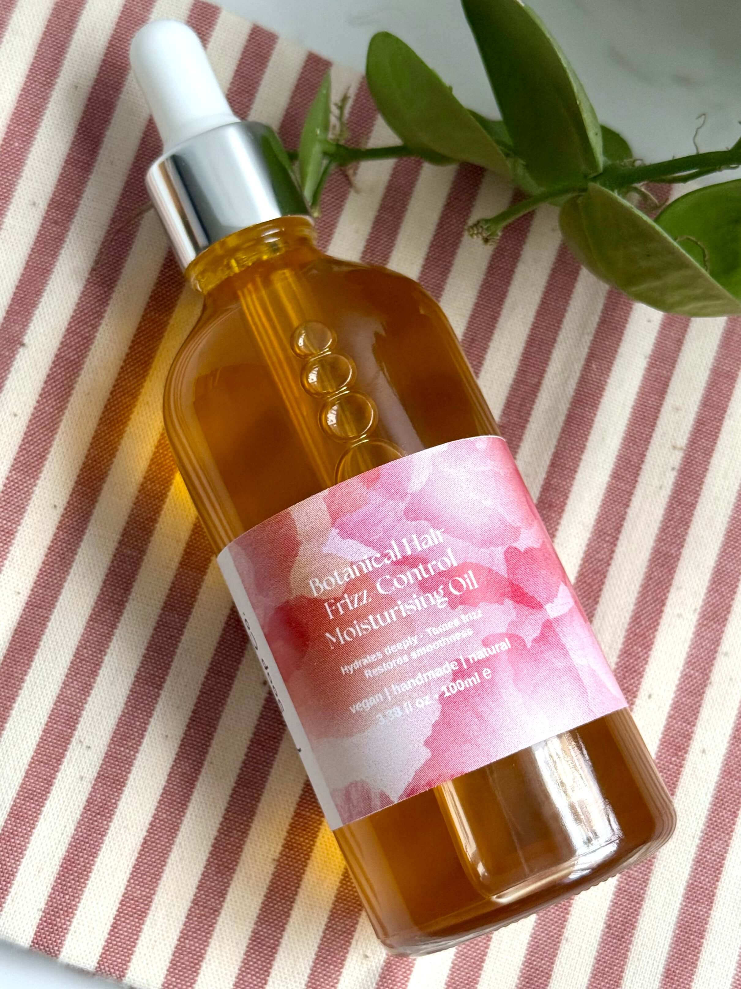 Natural Haircare oil bottle with a pink label on a striped fabric background