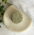 Natural Shampoo Bar - Balancing Act with leaf design on a white marble surface with a white towel and green leaves.