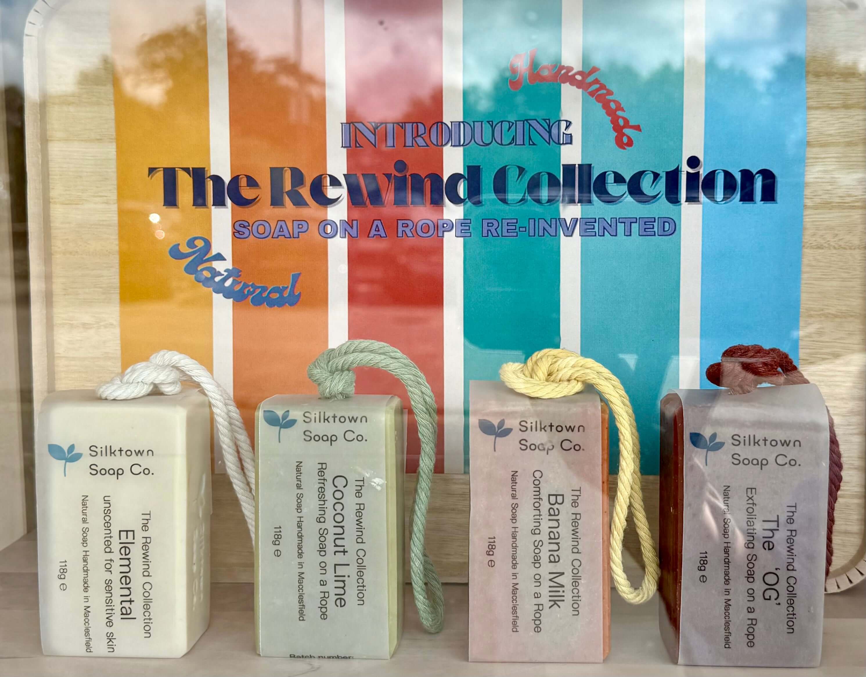 Bars of natural soap on a rope held in a box with coloured background