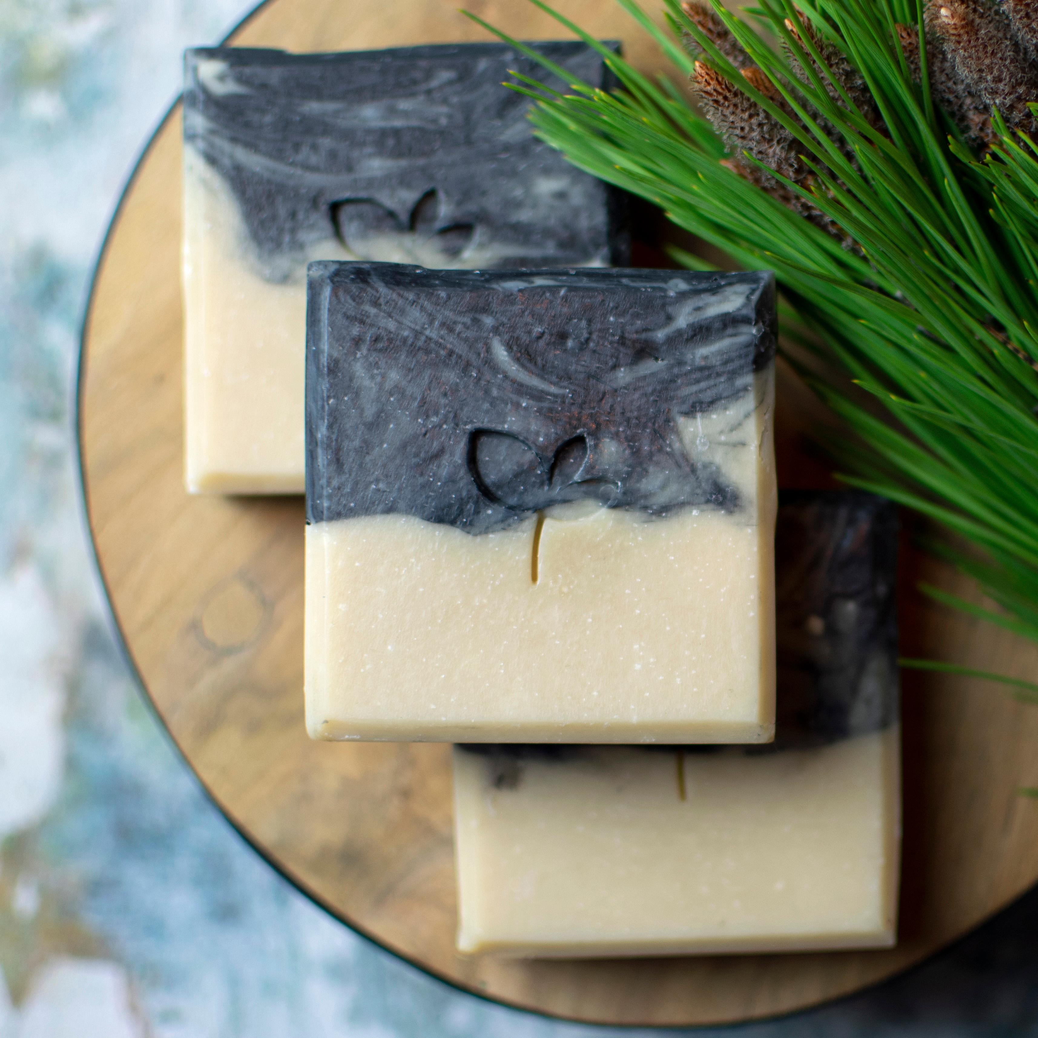 Cedarwood and Stout natural soap bars with charcoal with tree branch and wood
