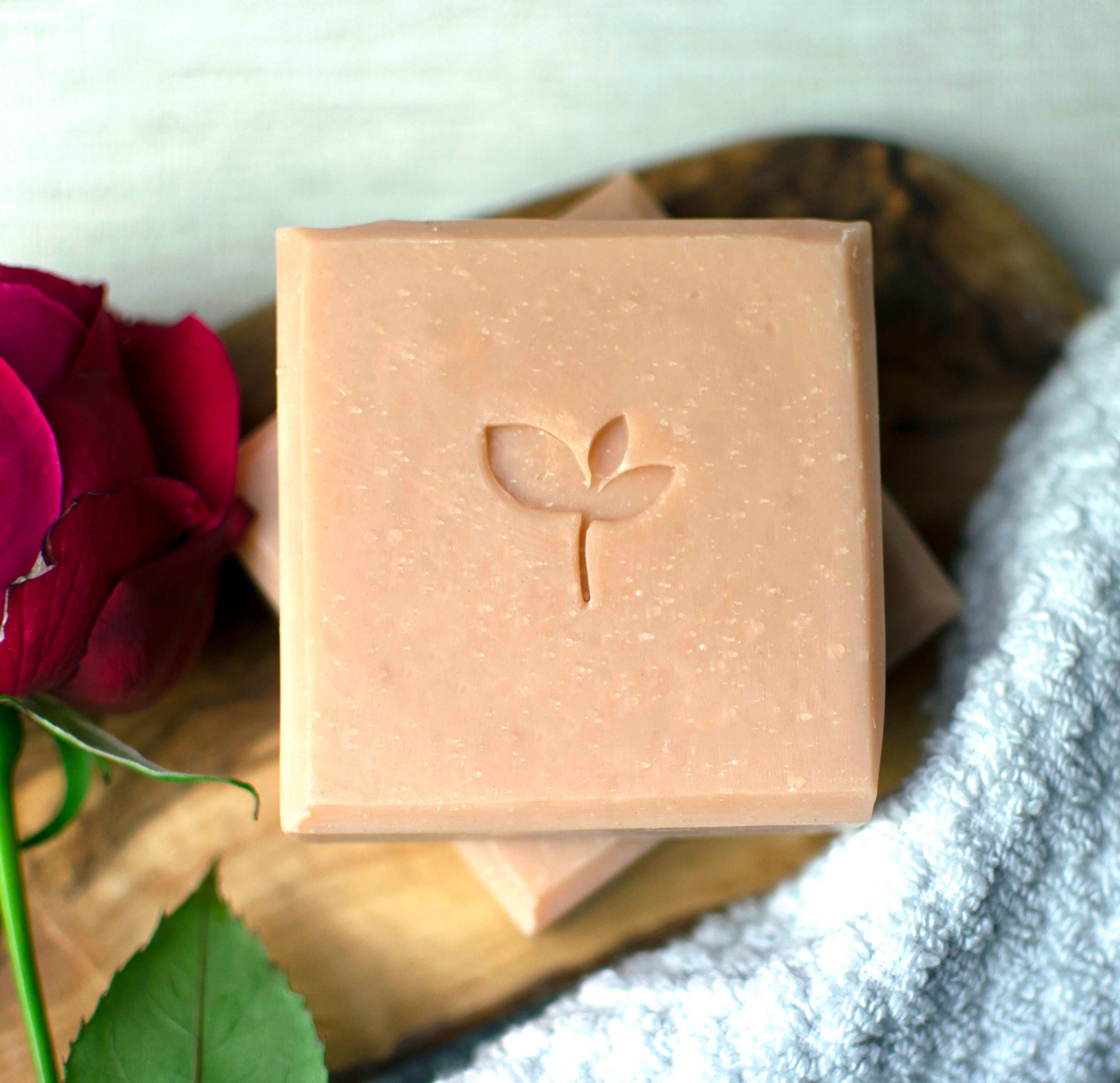 Enchanted handamde soap bar with a red rose and textile on wooden board