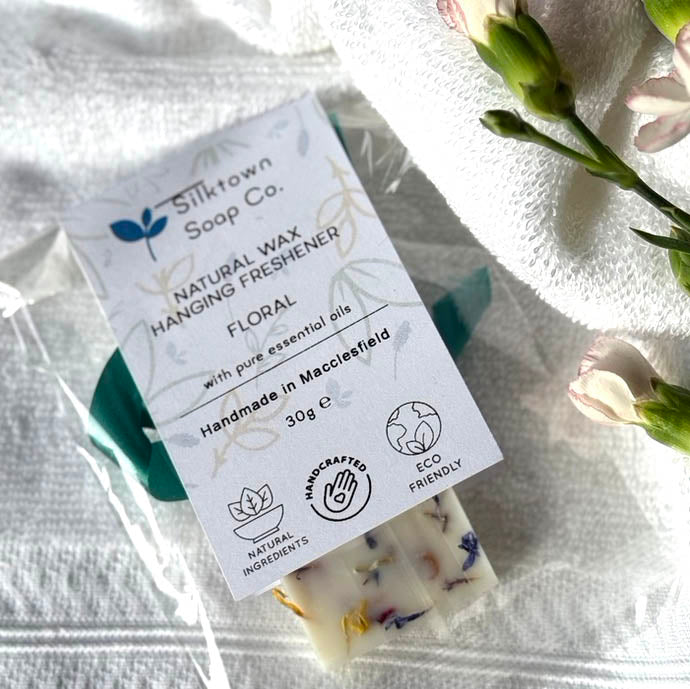 A packaged natural wax freshener tablet with floral aroma, handcrafted and labeled with eco-friendly and vegan attributes.