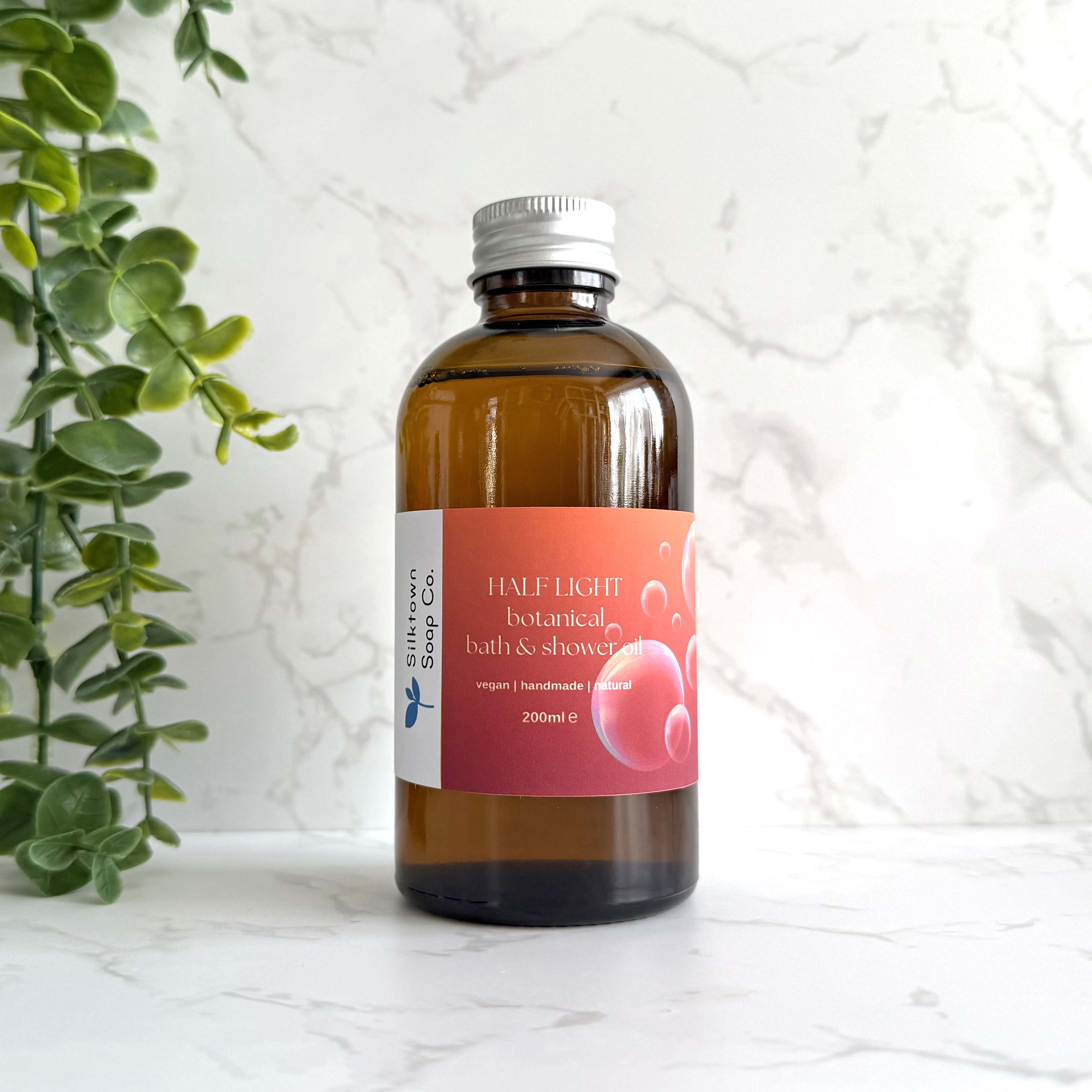 Half Light - Natural Skincare Foaming Bath and Shower Oil bottle with marble background and foliage