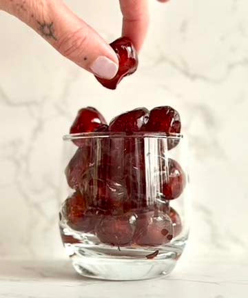 Wax Freshener inspiration, Hand placing gummy bears into a clear glass with a marble background