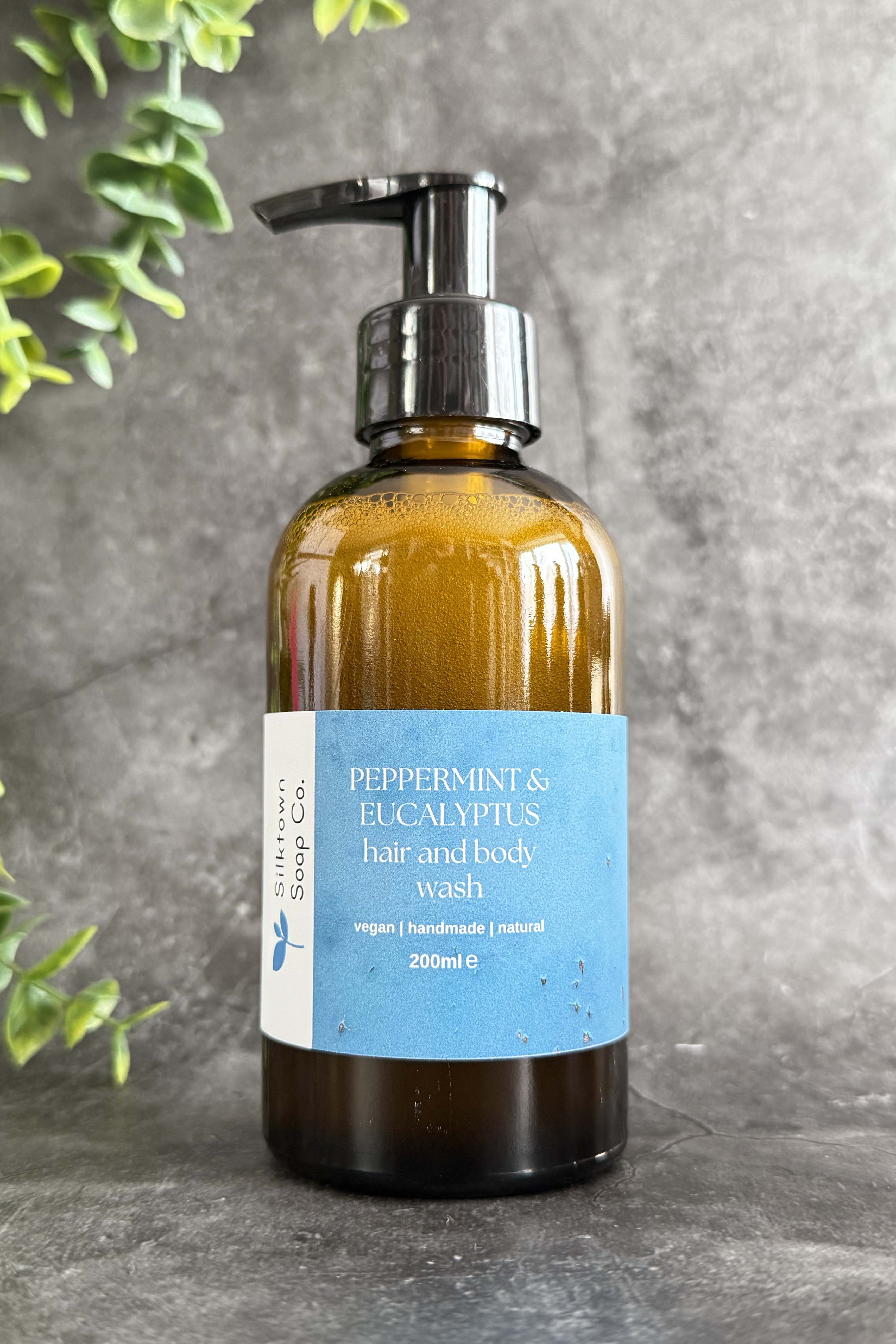 A pump bottle of Natural Hair & Body Wash with Peppermint & Eucalyptus, sulphate-free, vegan, and energizing cleanse labels.