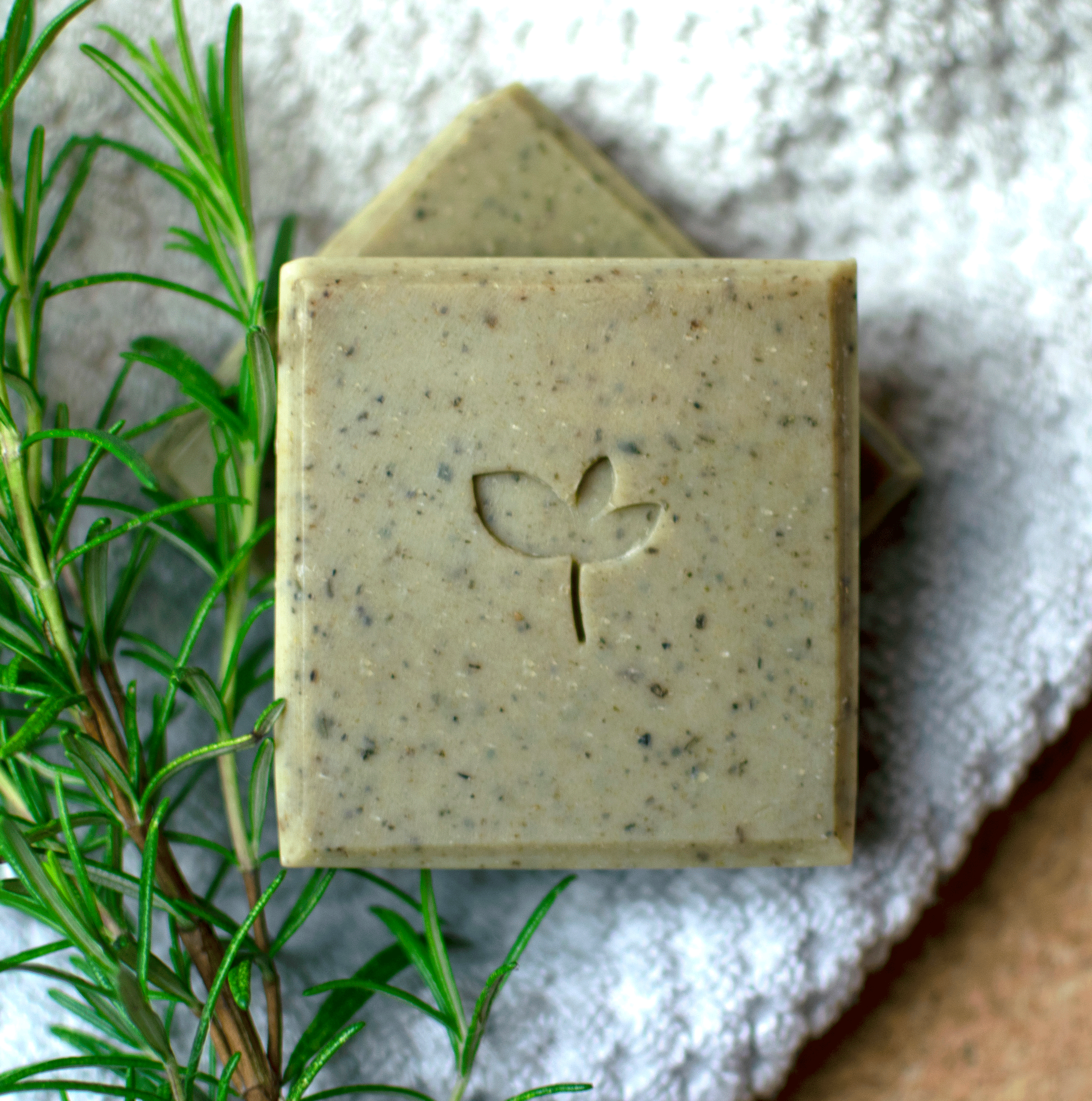 Persephone Natural soap bar on a towel with a rosemary sprig