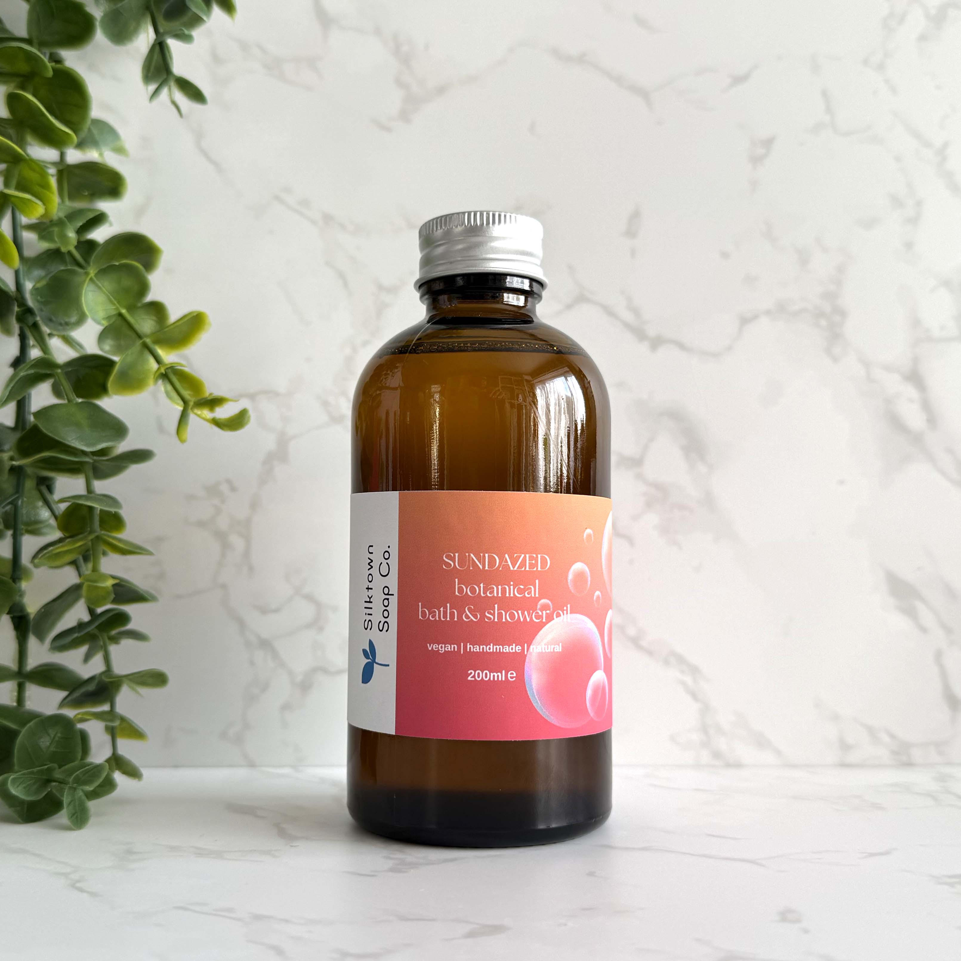 Sundazed - Natural Skincare Foaming Bath & Shower Oil with marble background and foliage