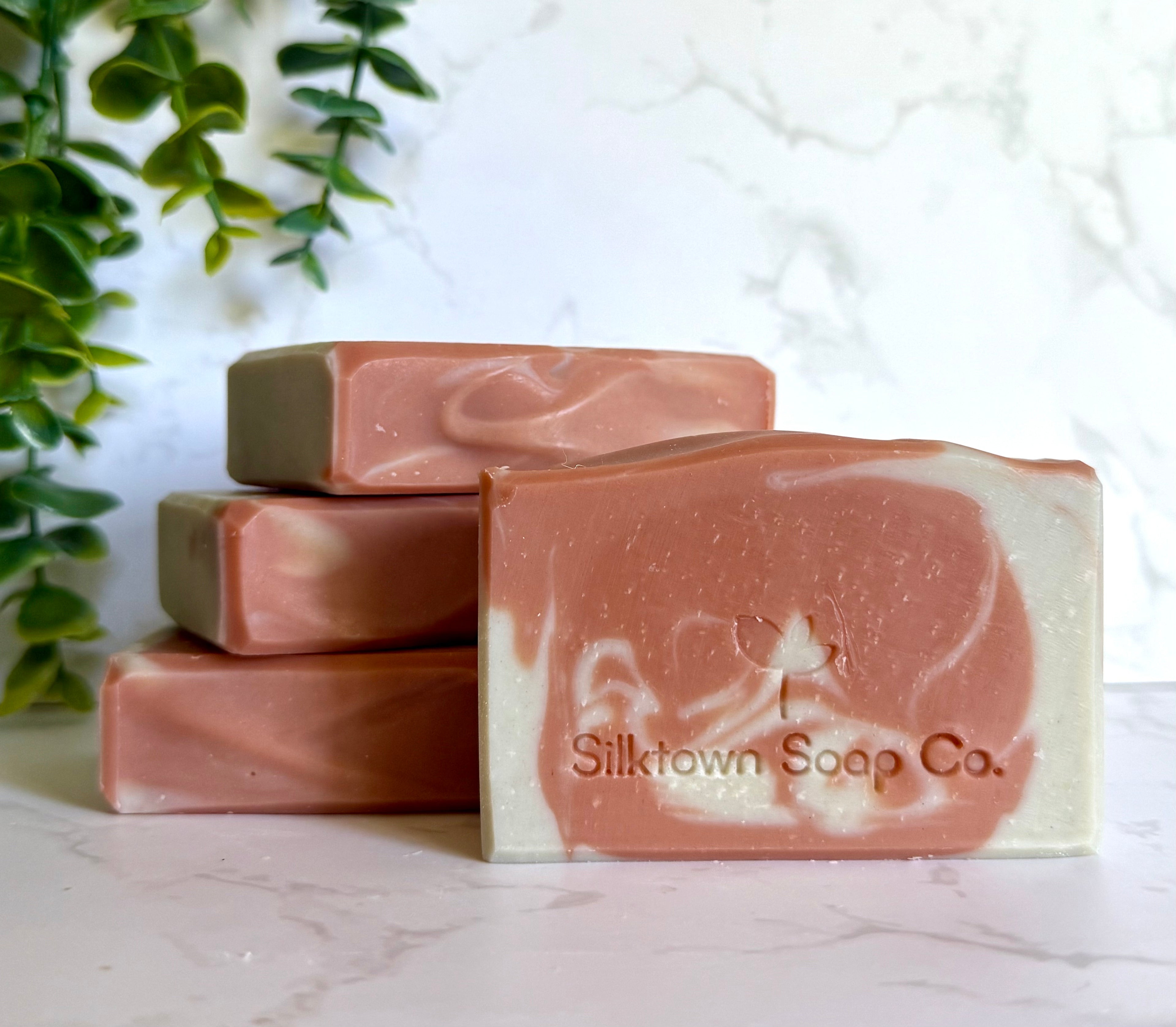 Three bars of soap with marbled design on a marble surface, branded &