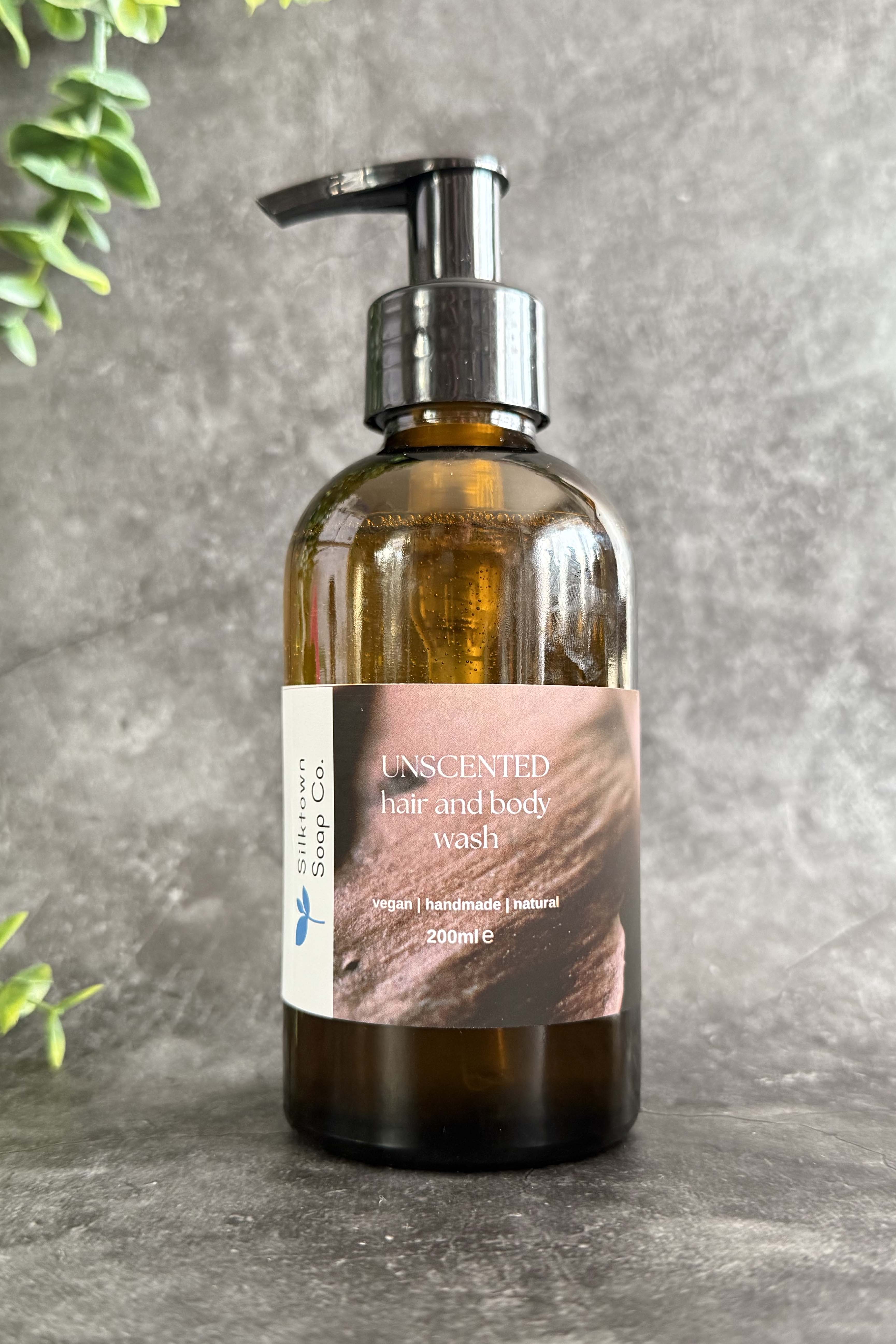 A clear pump bottle of unscented Natural hair and body wash with a label that reads &