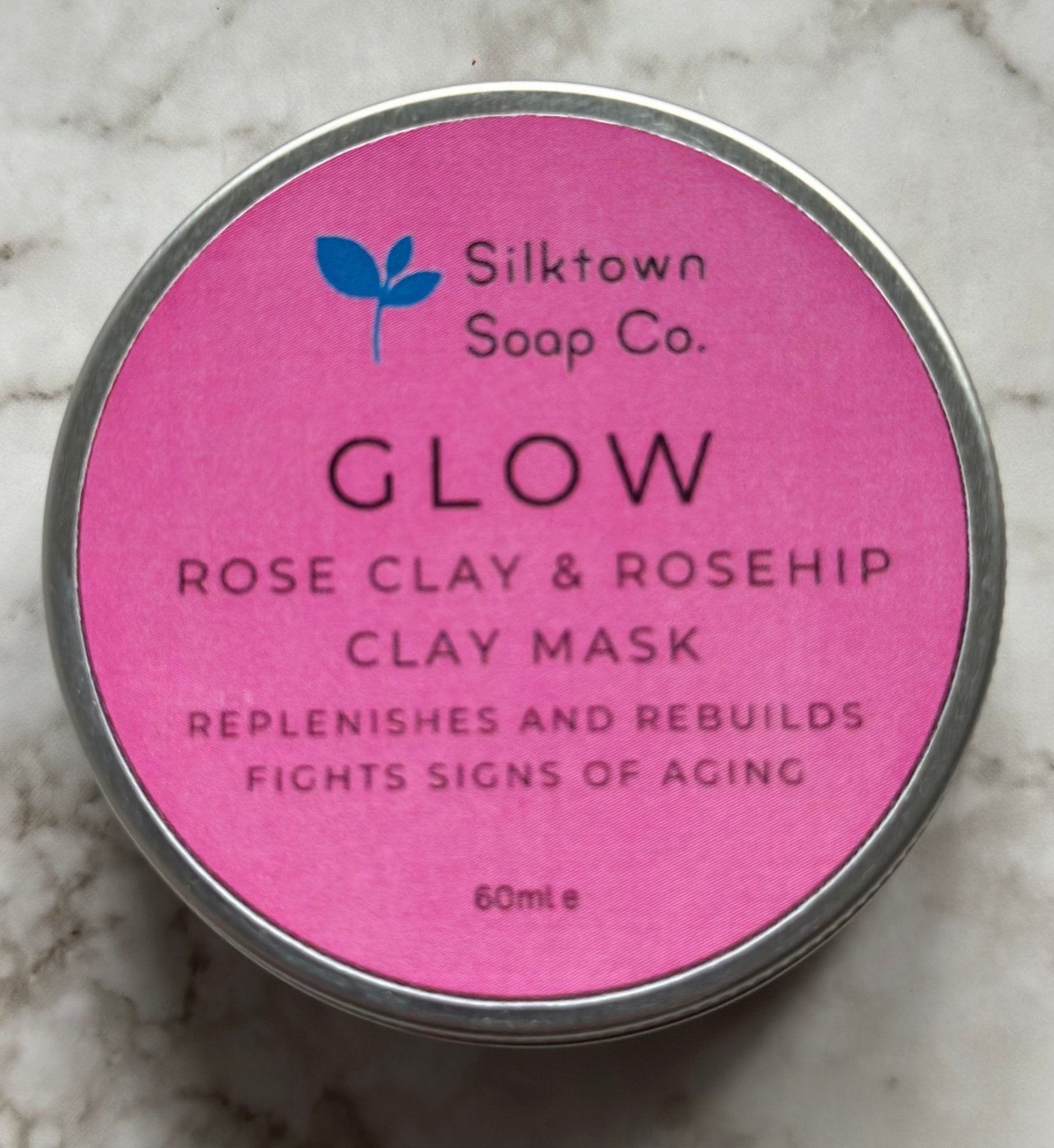 A tin of Glow natural clay mask on amarble background