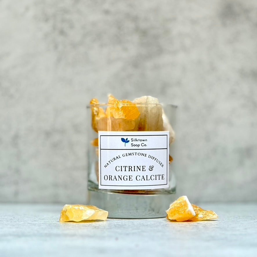 A glass jar on a white surface containing yellowish gemstones with a label reading &