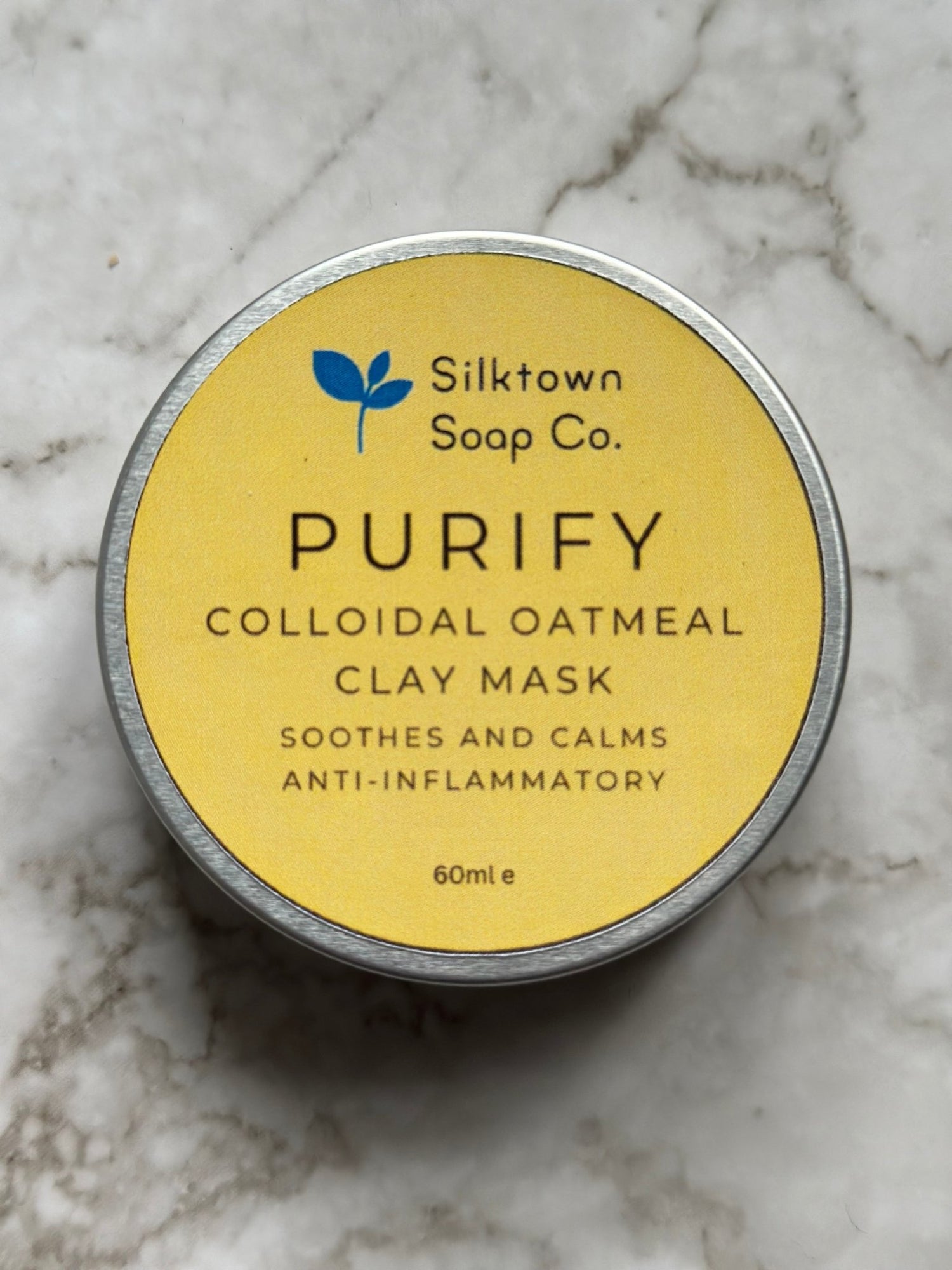 A tin of Purify natural skincare clay face masks on amarble background
