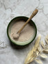 Purify Natural Clay Mask in a bowl with a wooden spoon and some foliage  before being mixed