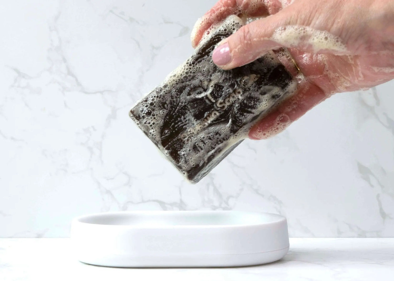 Woodsman Pine Tar Handmade Soap bar being held over a dish