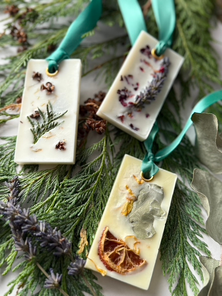 Natural Wax Hanging Fresheners with green ribbons on a background of foliage