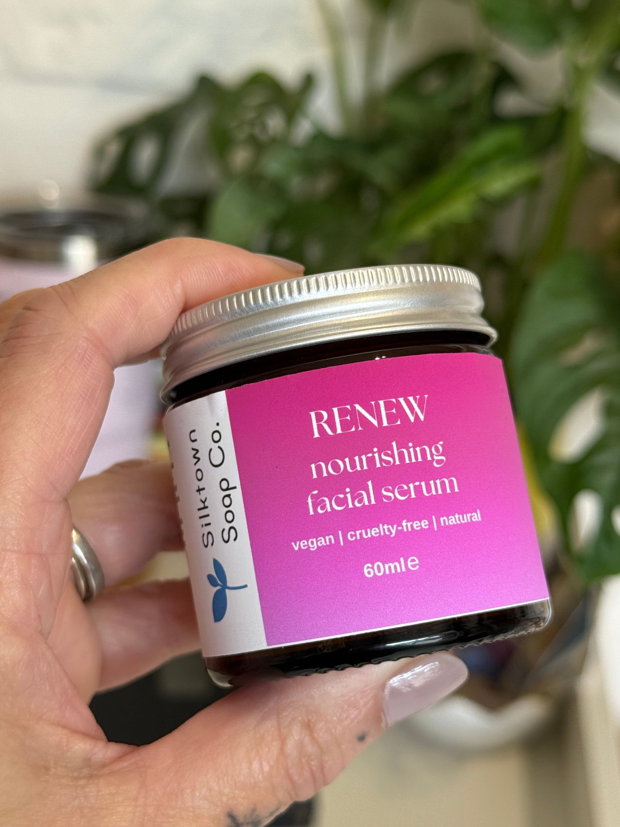 hand holding a jar of renew facial serum against a blurred background