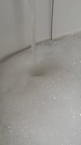 Dreamweaver Botanical Skincare Oil by Silktown Soap Co. shown while being poured into a bubbly bath, perfect for a soothing and relaxing experience.