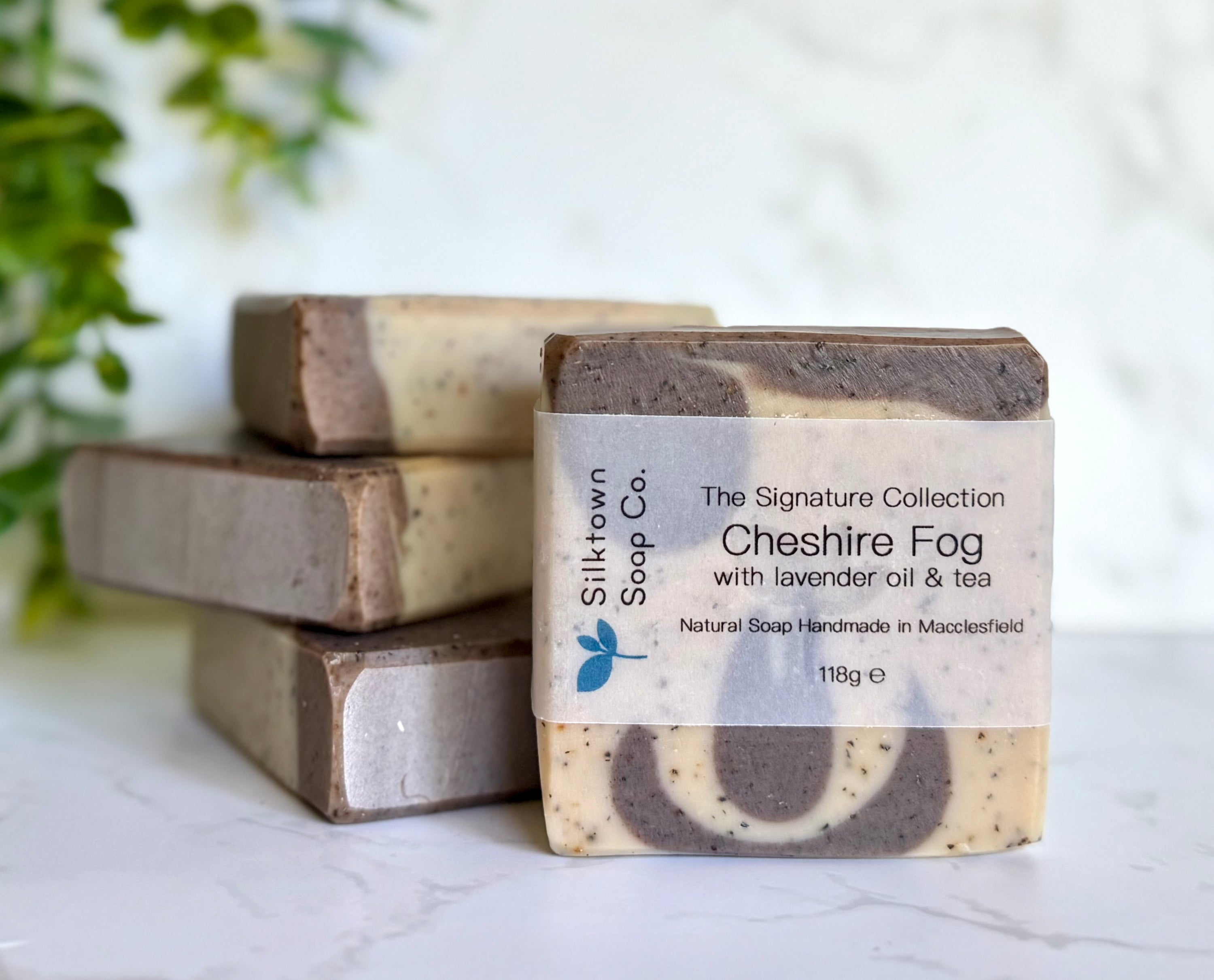 Four natural soap bars with a packaging label on a light surface with a blurred background