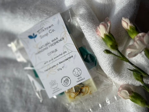Silkdown Soap Co. natural wax freshener on a white towel with flowers