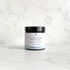 A jar of Silktown Soap Co. Clarifying Skin Cream with a black lid and white label, set on a light marble surface against a matching marble background.