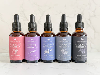 Five amber glass dropper bottles of Silktown Soap Co. diffuser oils lined up on a light marble surface.