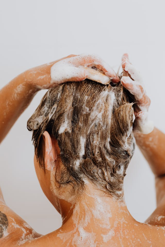 Person washing their hair with a Natural Shampoo Bar - Good Hair Day Shampoo on a plain background