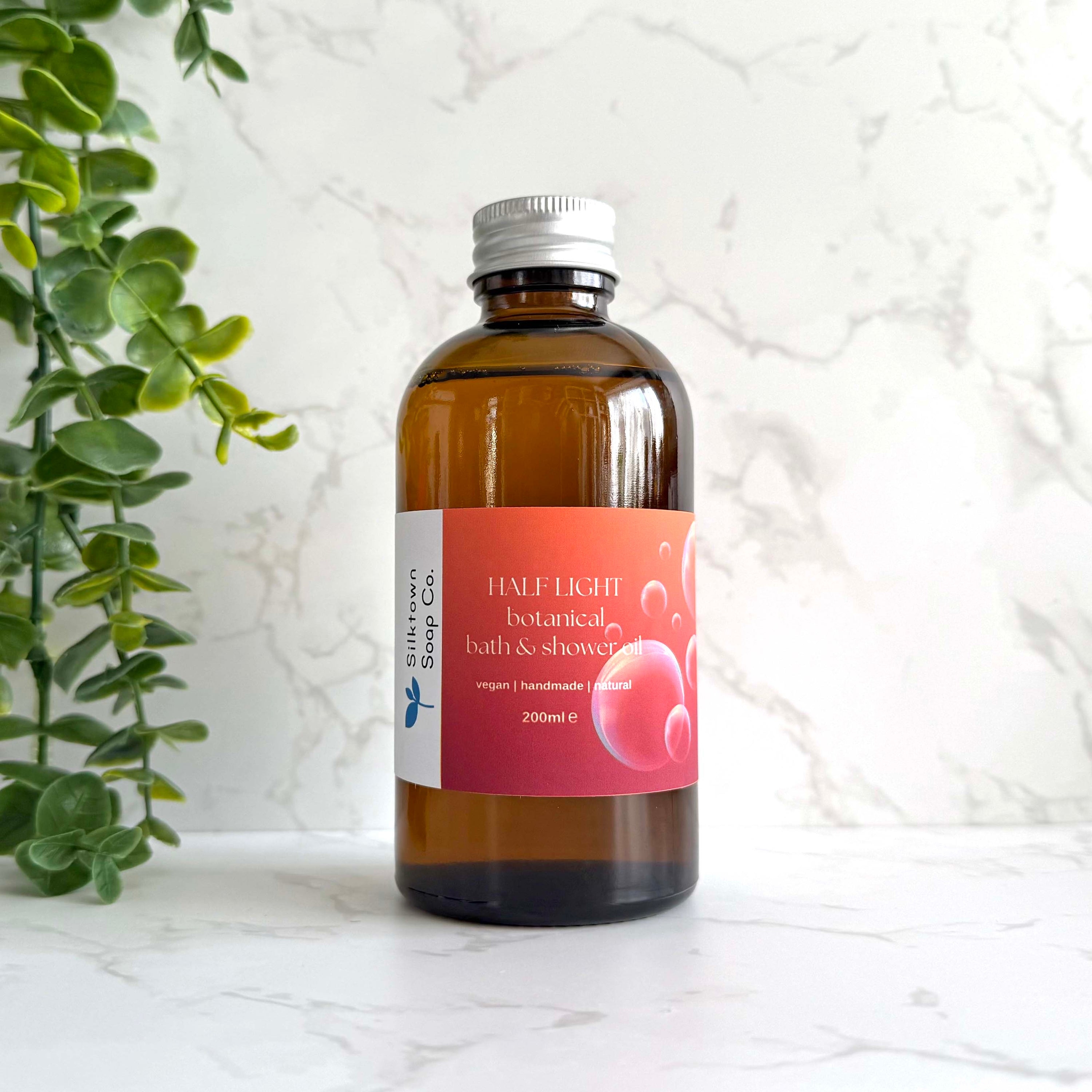 Half Light - Natural Skincare Foaming Bath and Shower Oil bottle with marble background and foliage