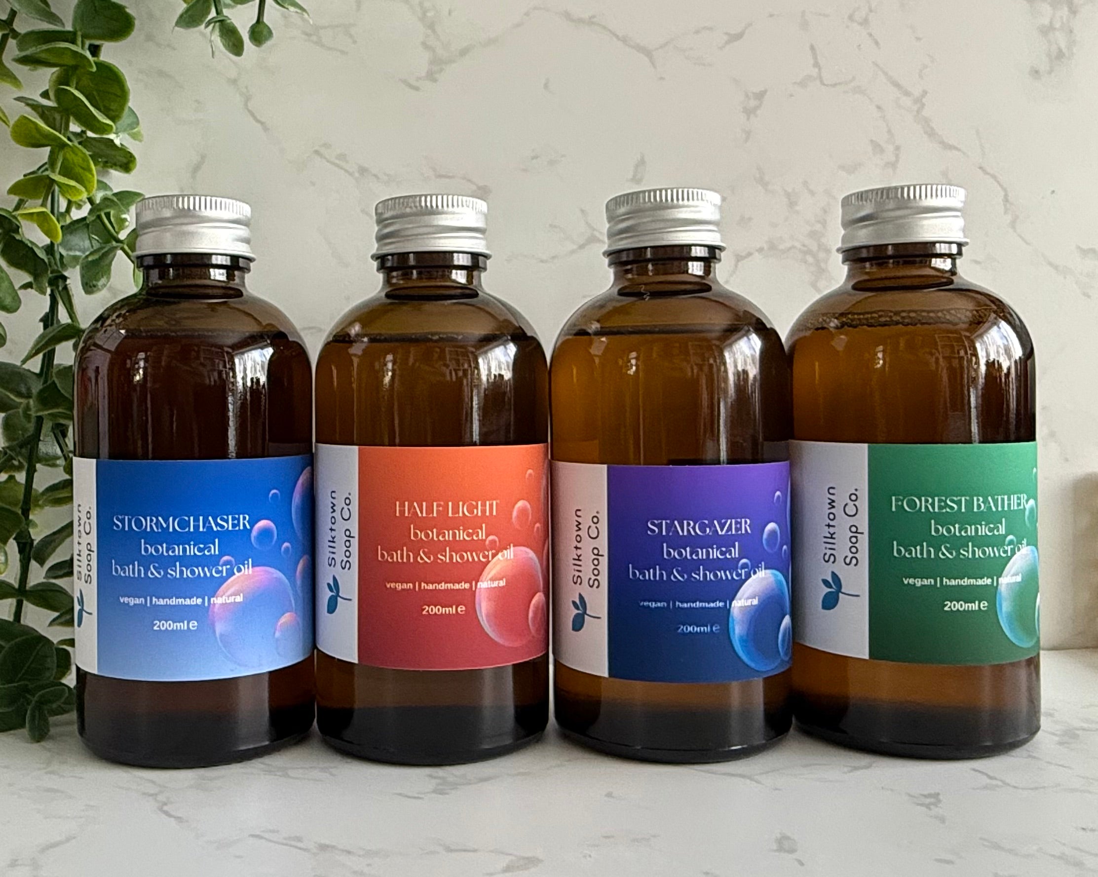 selection of natural skincare foaming  Bath &amp; Shower Oils with marble background and foliage