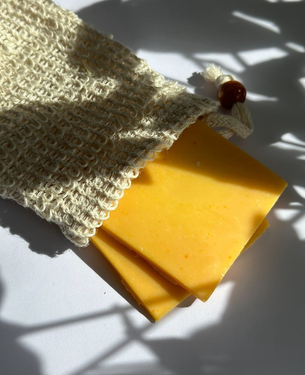 A close-up of the Zero-Waste Soap Bag by Silktown Soap Company, showcasing beautiful yellow soap pieces peeking out of a natural, handmade bag. This ethical and sustainable option is perfect for those seeking vegan and natural skincare solutions while embracing a zero waste lifestyle.
