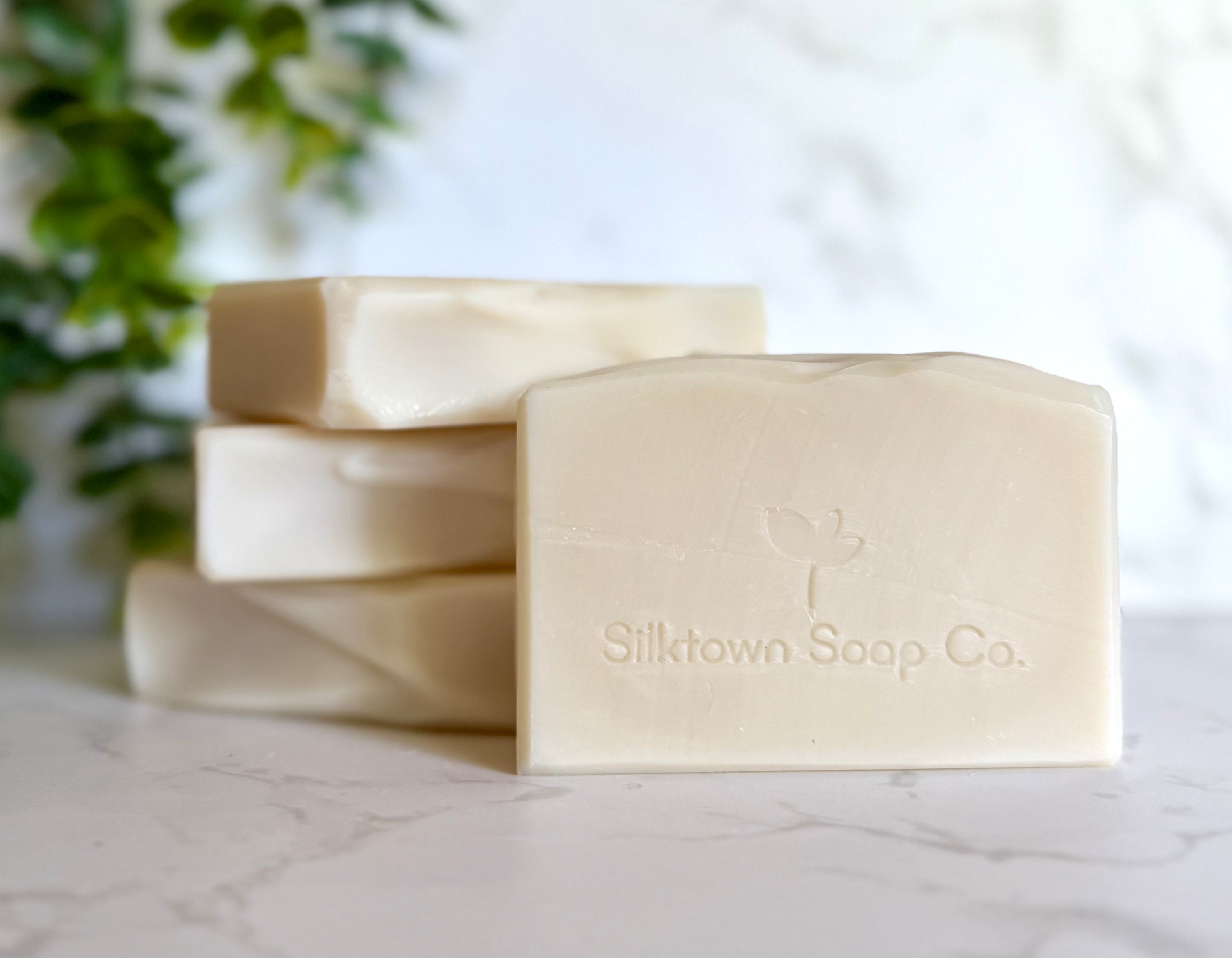 Silktown Soap Co. natural soap bars on a marble surface with a blurred plant in the background