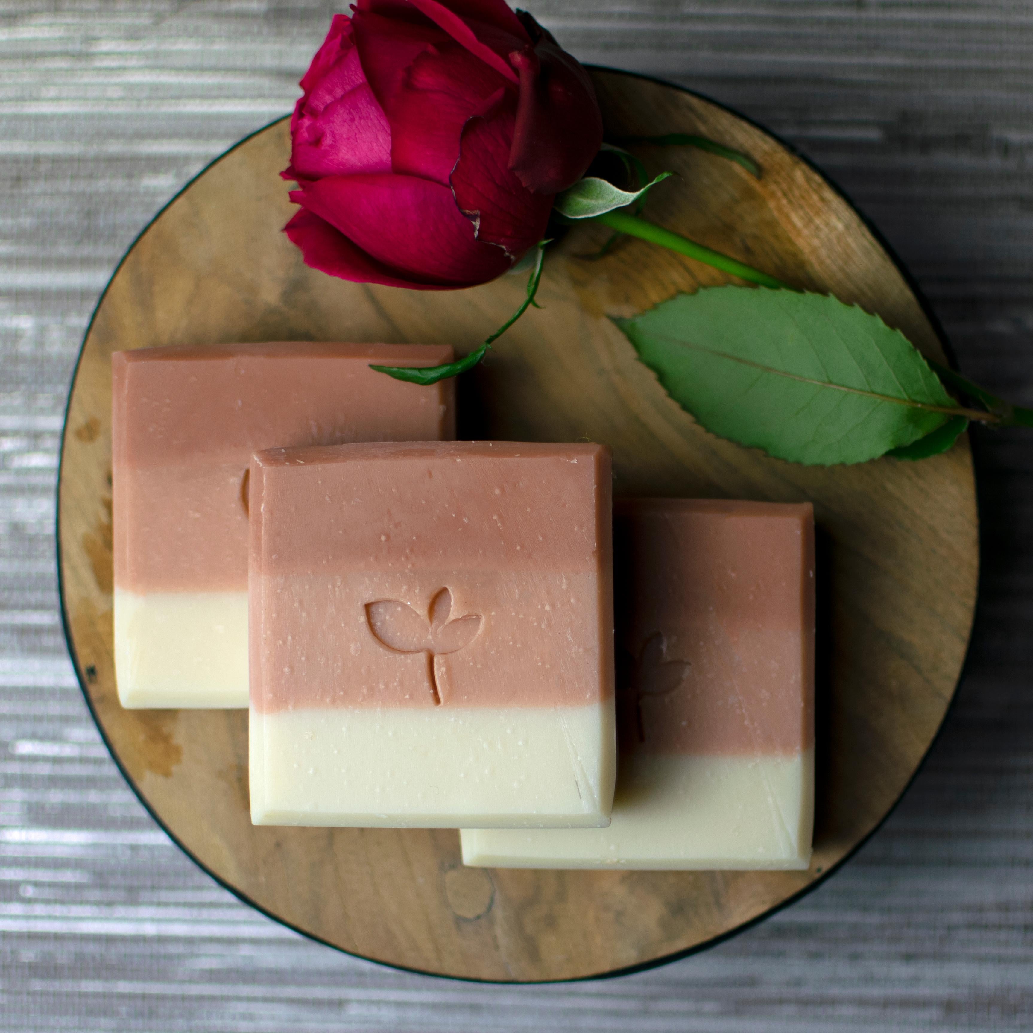 Midsummer Meadow handmade soap bars with a red rose on a wood board