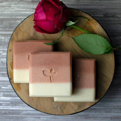 Midsummer Meadow handmade soap bars with a red rose on a wood board