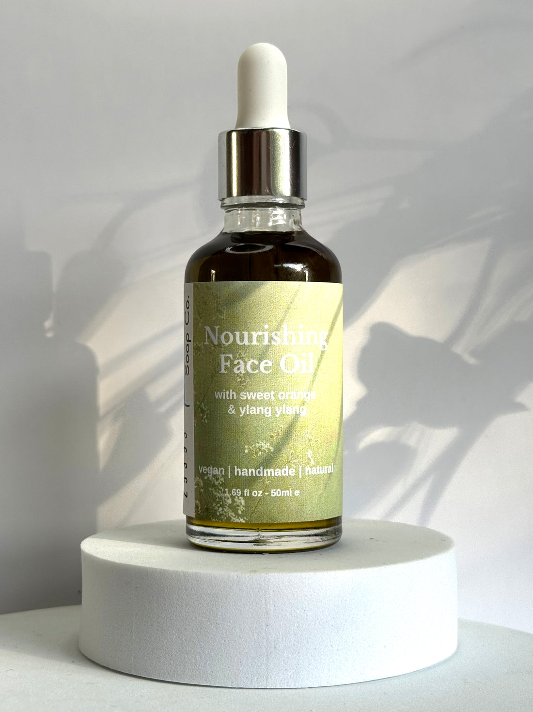 Bottle of Nourishing Face Tea on a white pedestal with a neutral background