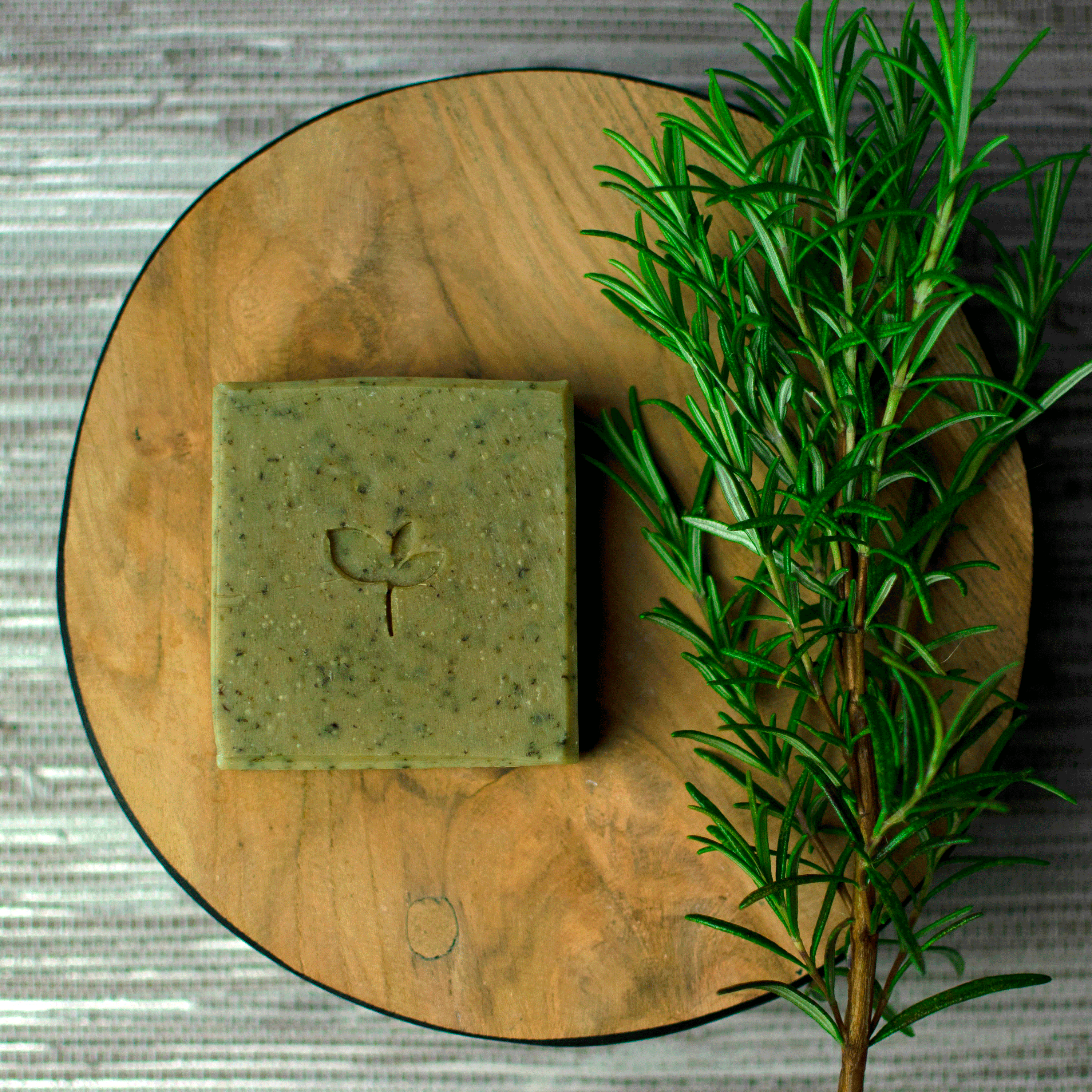 Persephone Natural soap bar on a wooden board with a rosemary sprig