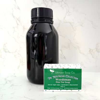 A black glass bottle with a black cap stands next to a rectangular box of &