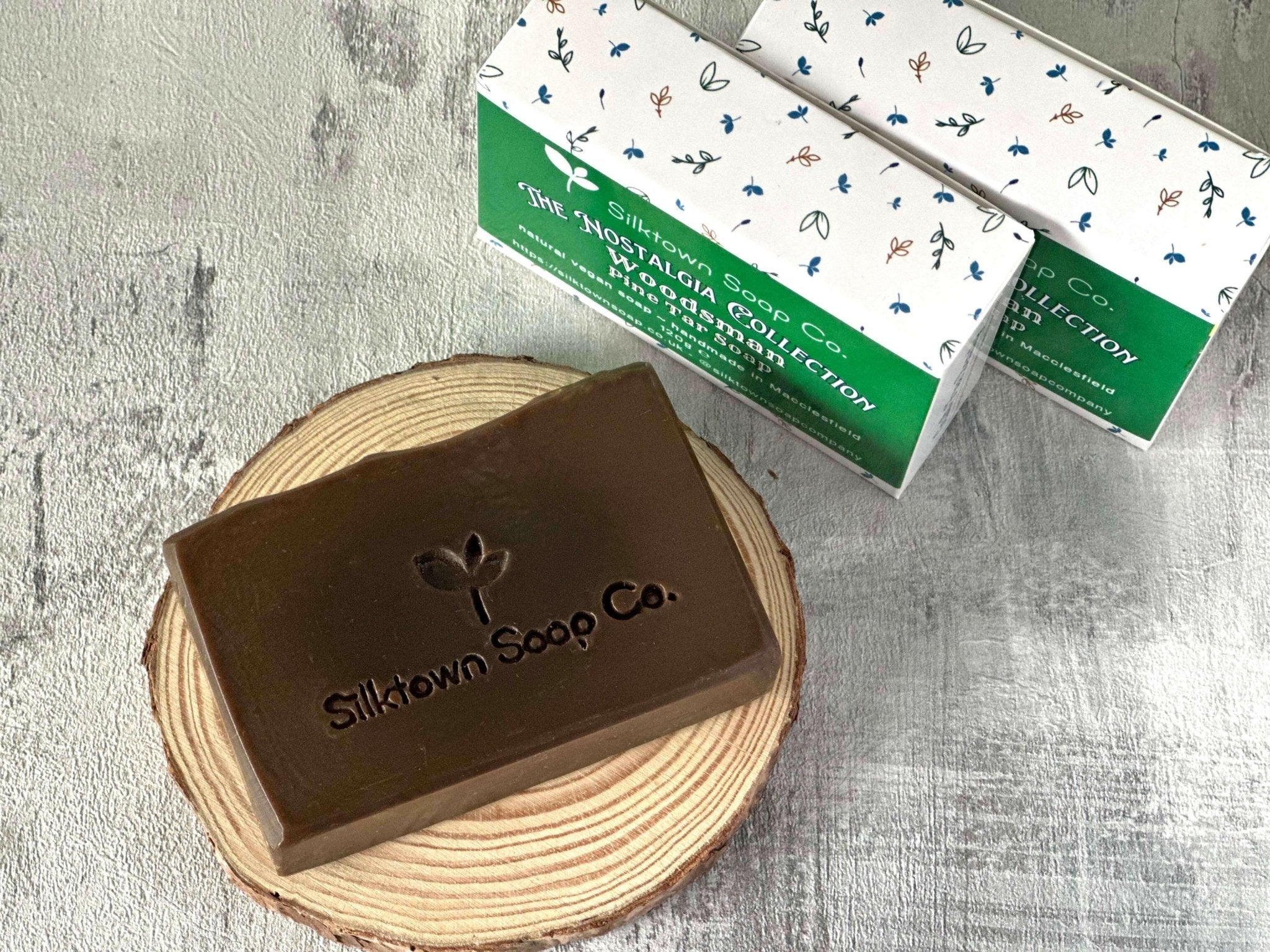Woodsman natural Pine Tar Soap on wooden disk with packaged bars