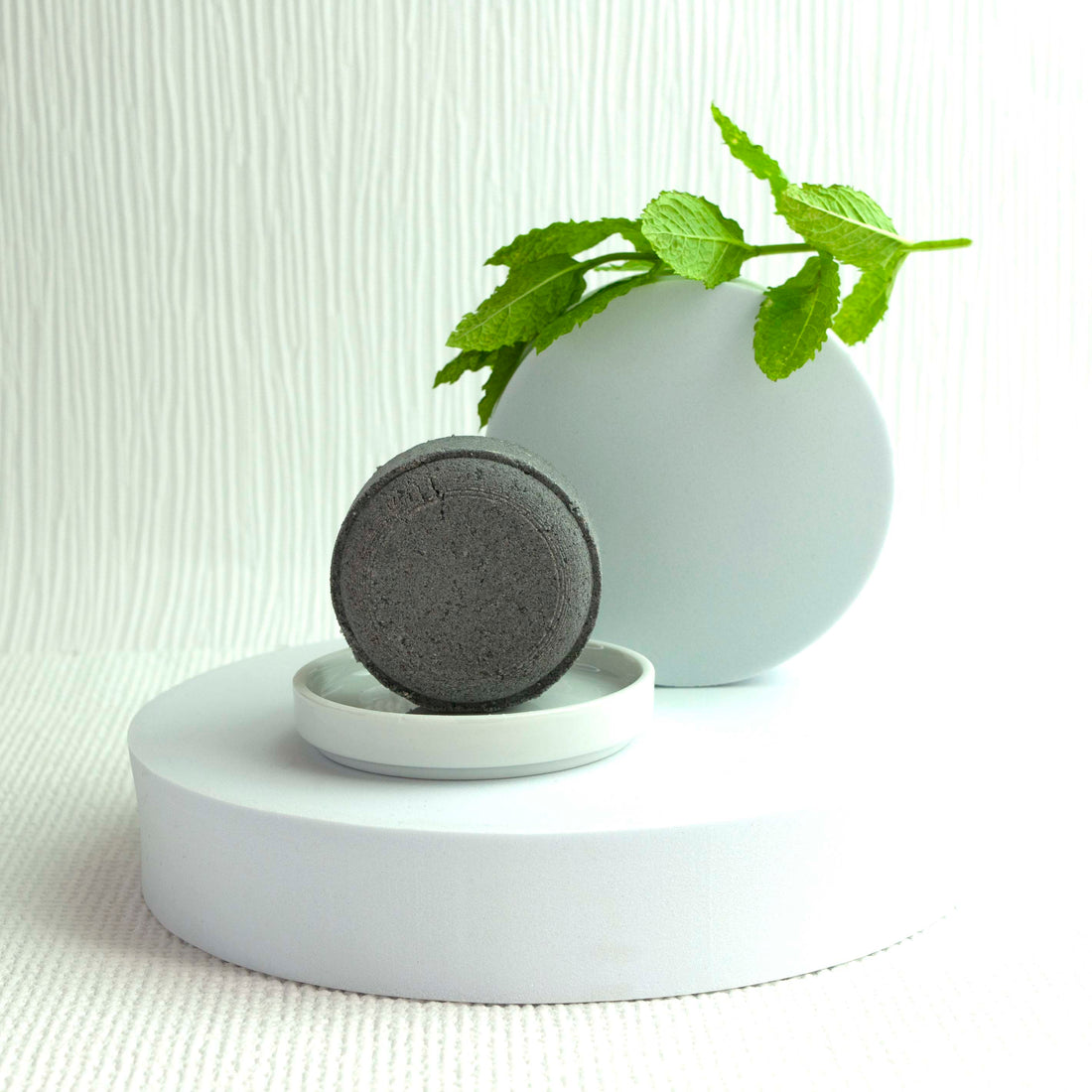 A Walk in the Clouds - Natural Skincare Bath Bomb displayed in a dish with mint and white display plinthes