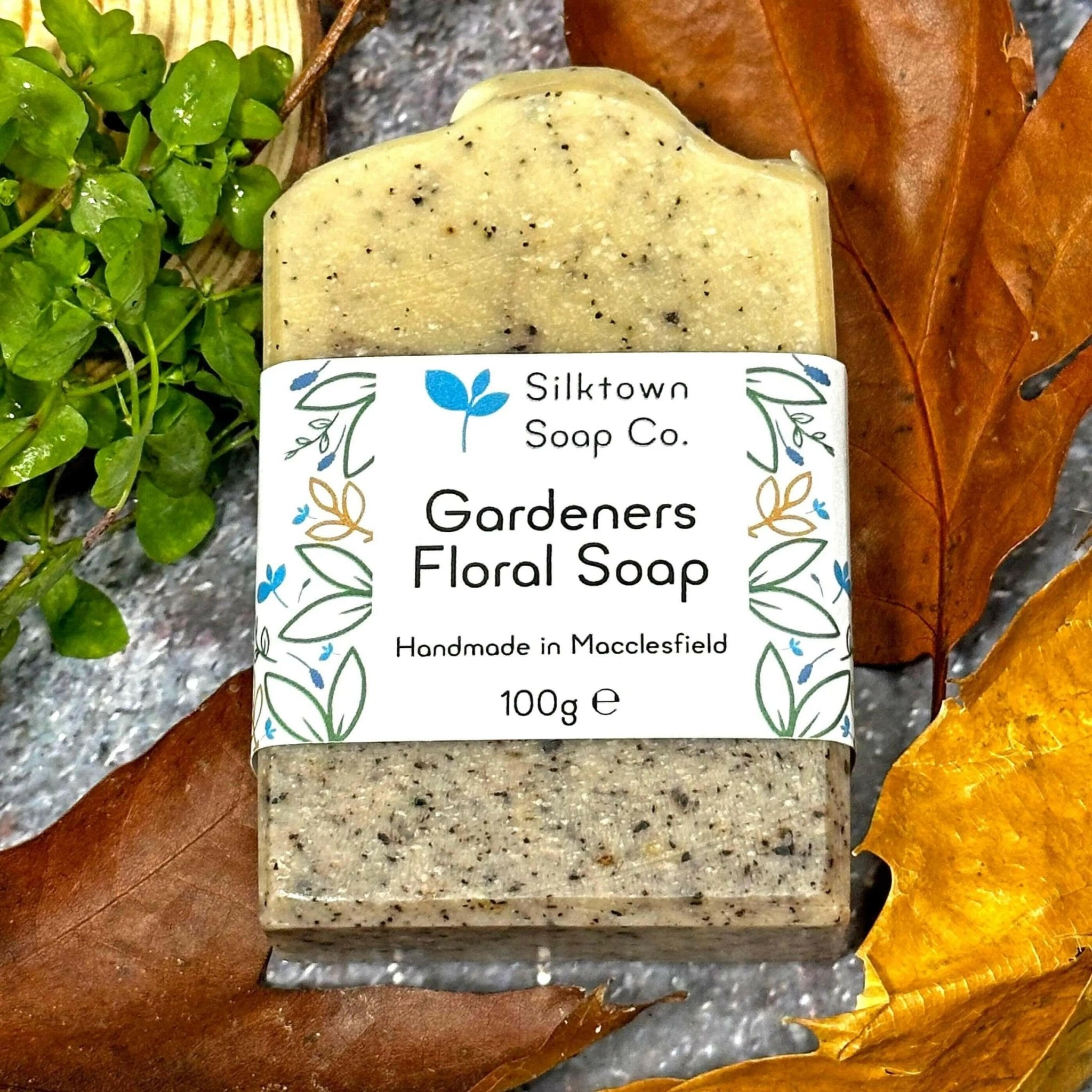 gardeners floral natural soap with label amongst leave foliage, wood and stone
