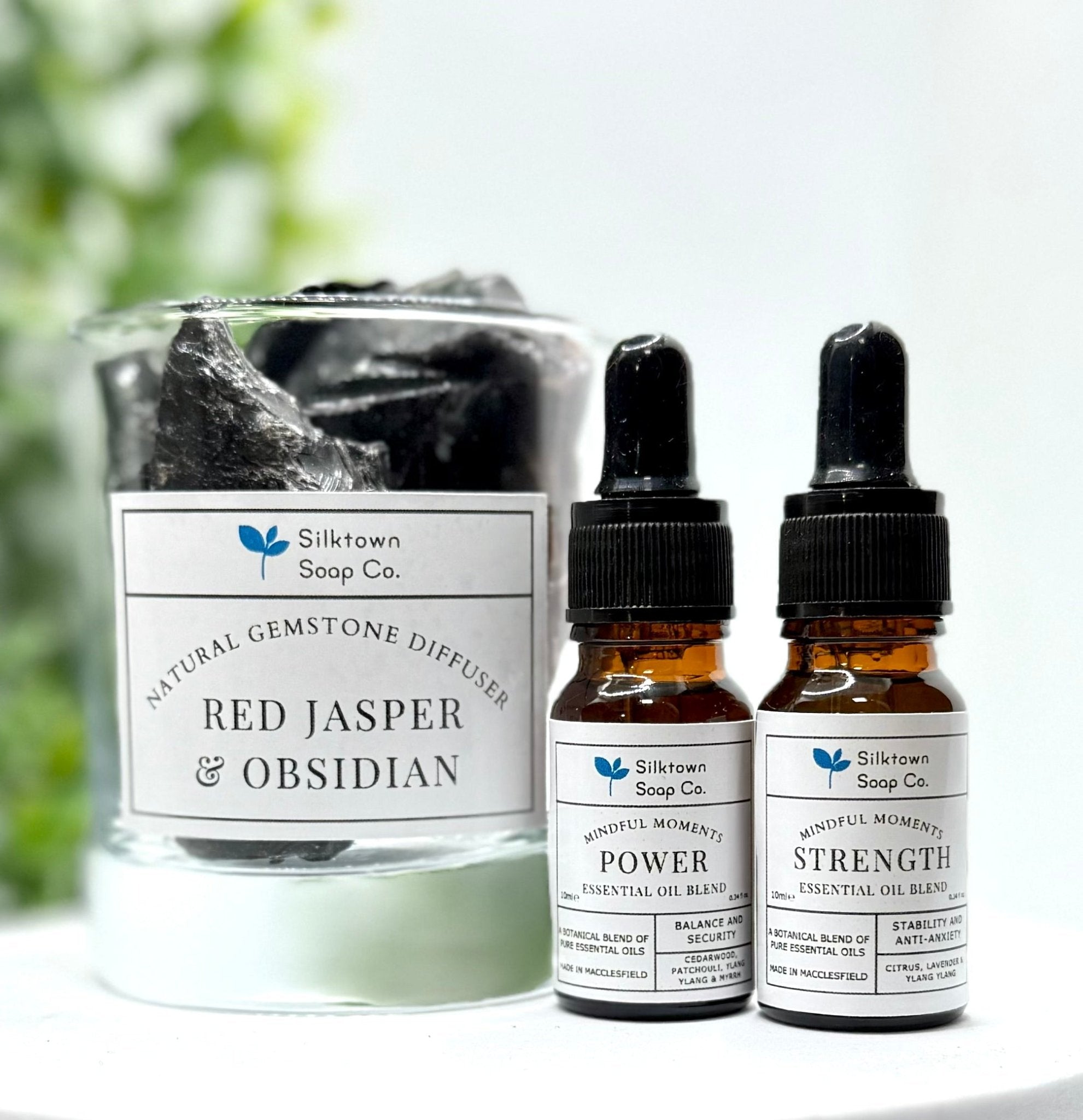 Gemstone diffuser with two brown bottles of essential oil blends with foliage in the background