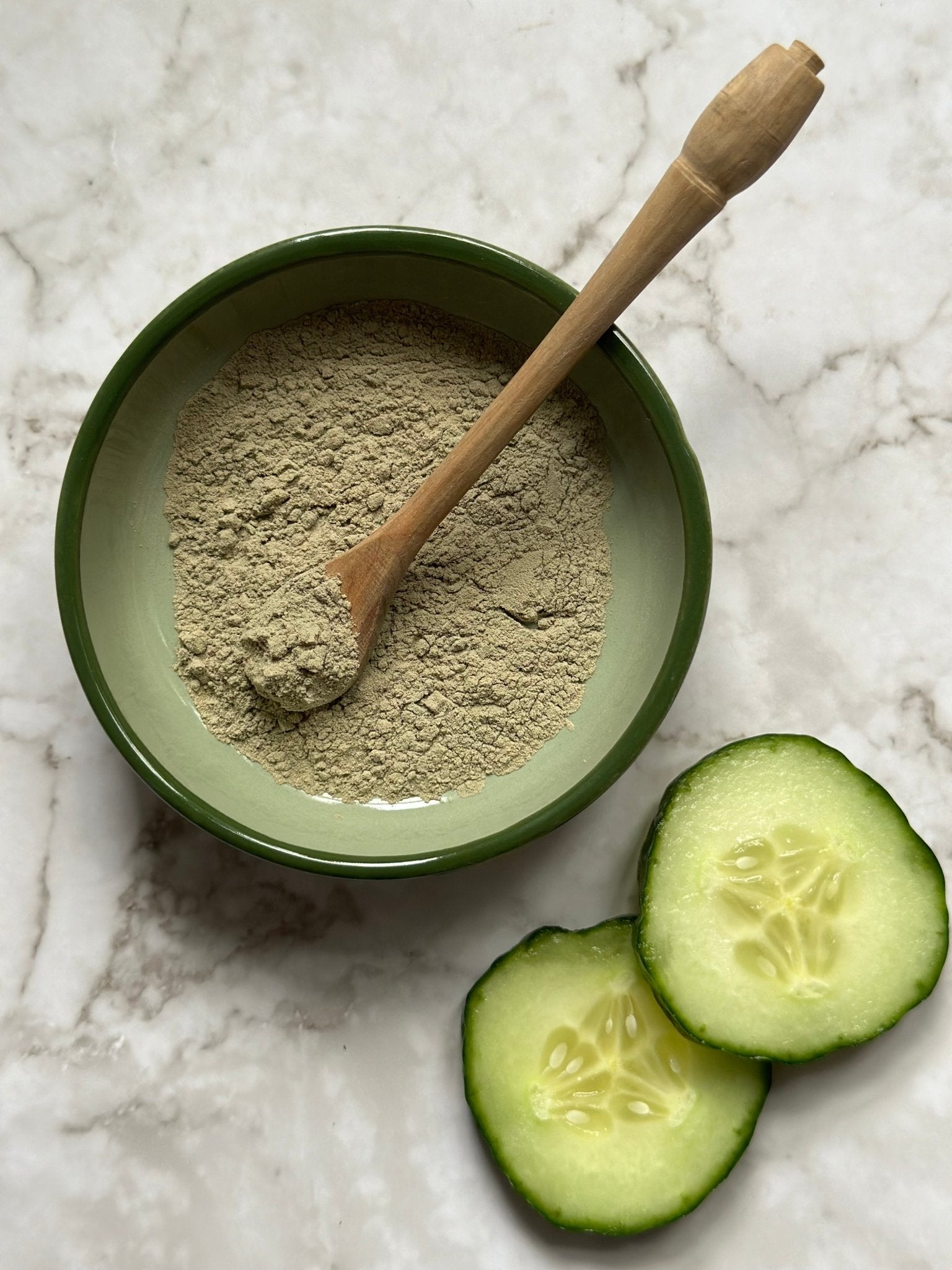 Refresh Natural Clay Mask in a bowl with a wooden spoon and some fresh cucumber slices before being mixed 